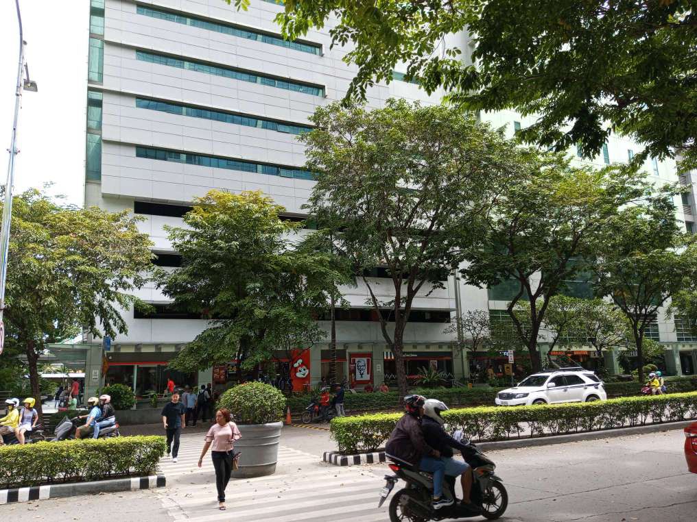 i3 building photo taken from Mabuhay Tower, Cebu IT Park. You can see motorcycles and cars passing by with pedestrians on crosswalk. Jollibee, KFC, and Orange Brutus is visibly in the ground floor.