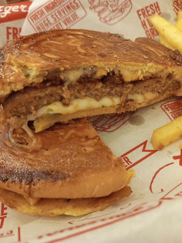 Zoom photo of Zark's Cheeseburger cut in half showing the patty, cheddar cheese, with jalapeños in smashed buns.