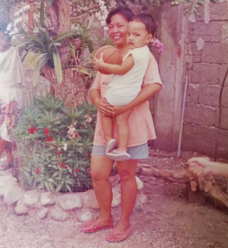 Mother Conchita Markines Laviña holding her youngest son Robin Markines Laviña. The child is holding a basketball. An old photo from the 90s.