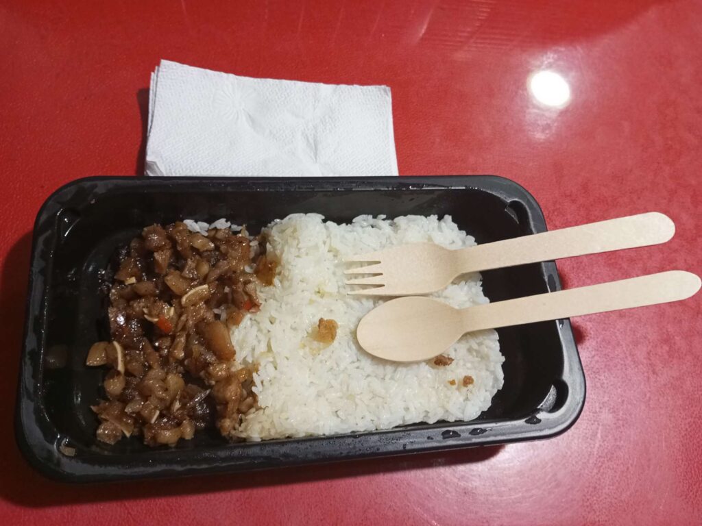 Uncle Brew pork sisig meal presentation on a black food container. It comes with wooden spoon and fork and some tissues.