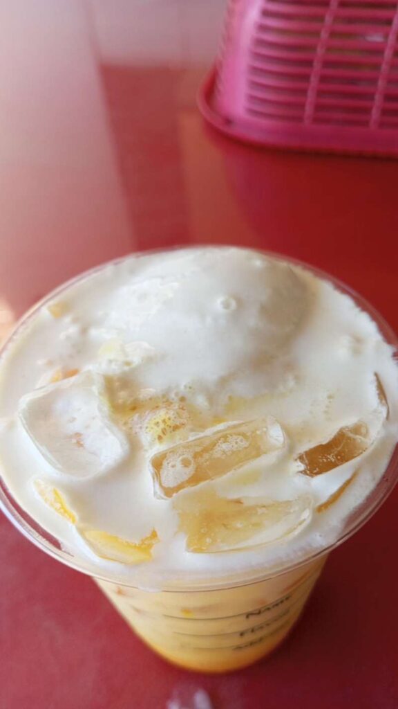 Ice Cream Float on top of the Mango Latte Iced Coffee Drink. The background is a red color table.